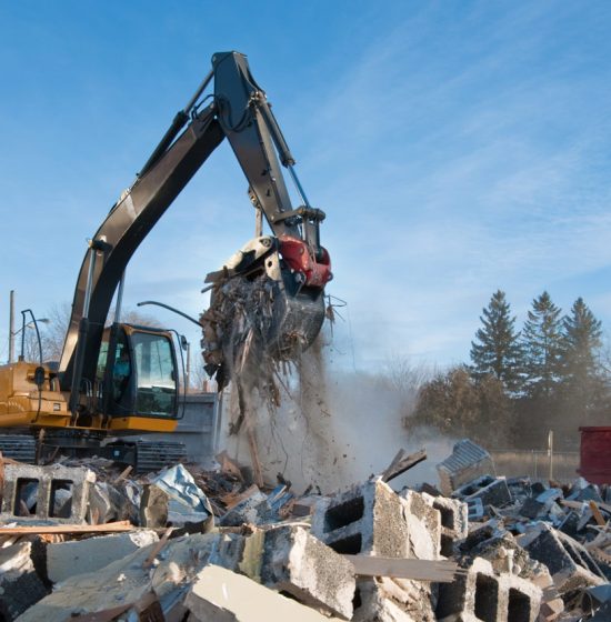 An excavator equipment removing concrete blocks and debris from demolition of a property