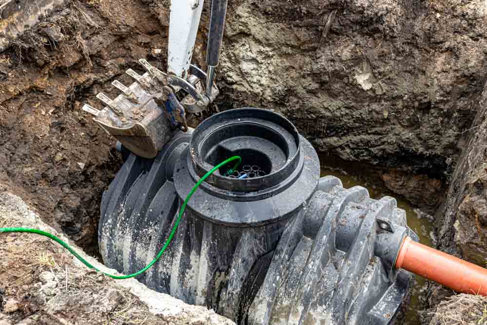 Installation of a single-chamber home sewage treatment plant, the excavator raises the tank.