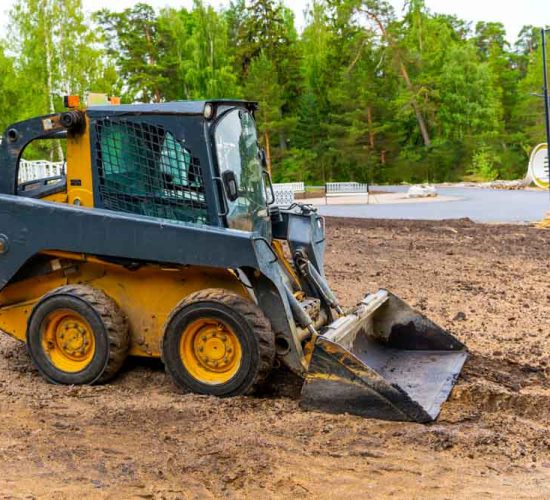 mini loader with bucket. A loader with a bucket clears the site for construction. Machine for moving soil, sand and bulk materials